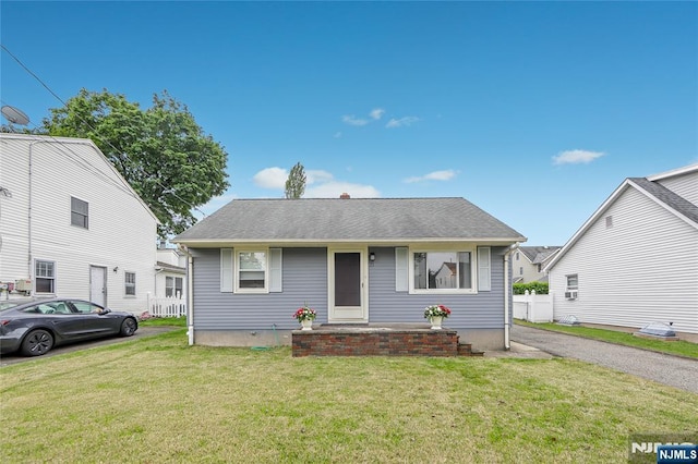 bungalow with a front lawn and a shingled roof