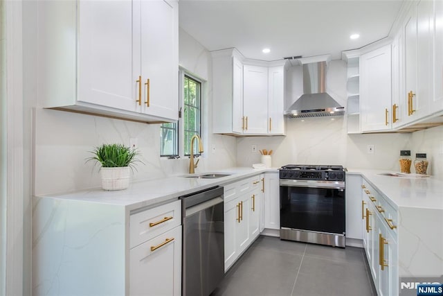 434 Argyle St, Oradell, NJ 07649 - kitchen featuring stainless steel dishwasher, wall chimney range hood, gas range oven, a sink, and white cabinets