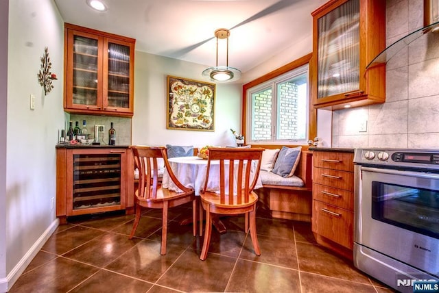 dining space with beverage cooler, breakfast area, a dry bar, dark tile patterned flooring, and baseboards