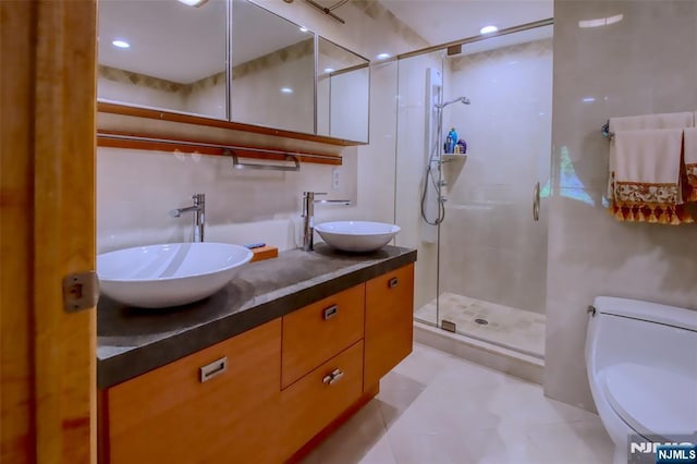bathroom with toilet, a shower stall, and double vanity