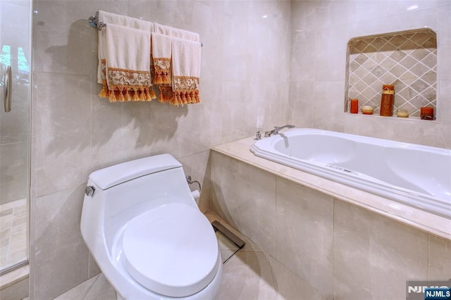 bathroom featuring tile walls, toilet, and a garden tub