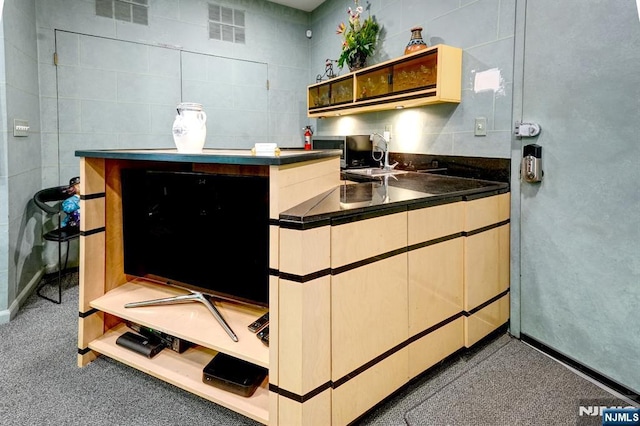 kitchen with dark countertops, open shelves, and a sink