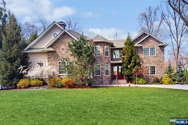 view of front of home with stucco siding, a front lawn, and stone siding