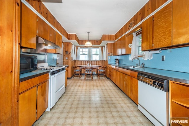 kitchen featuring white appliances, a sink, light flooring, and brown cabinetry