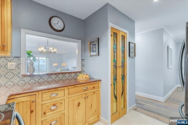 kitchen with baseboards, decorative backsplash, a chandelier, stainless steel refrigerator, and light wood finished floors