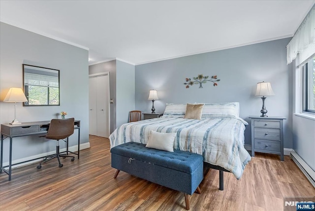bedroom featuring wood finished floors, multiple windows, crown molding, and baseboard heating
