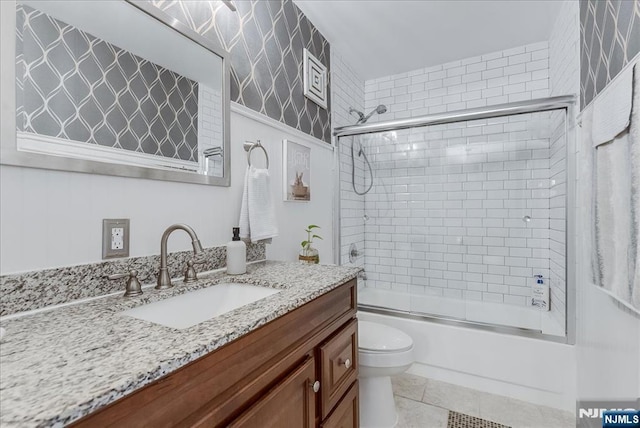 bathroom with toilet, enclosed tub / shower combo, vanity, and tile patterned floors