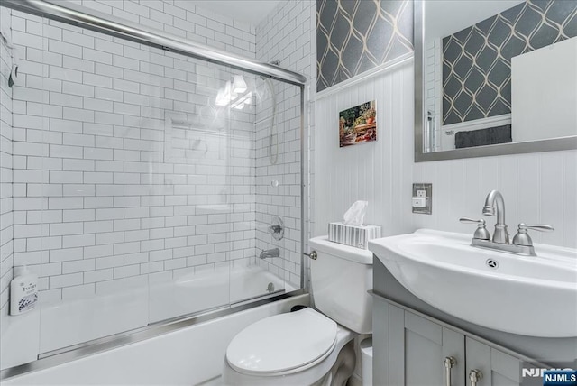full bathroom with toilet, bath / shower combo with glass door, vanity, and wallpapered walls