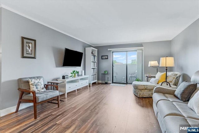 living area featuring wood finished floors, ornamental molding, and baseboards