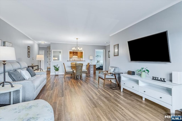 living room featuring crown molding, a chandelier, wood finished floors, and baseboards