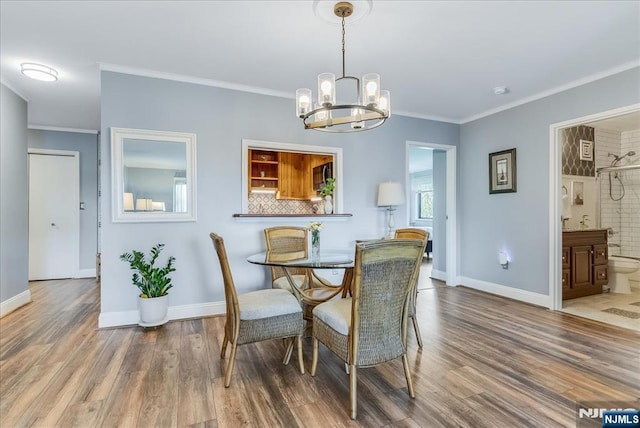 dining space with a chandelier, baseboards, wood finished floors, and crown molding