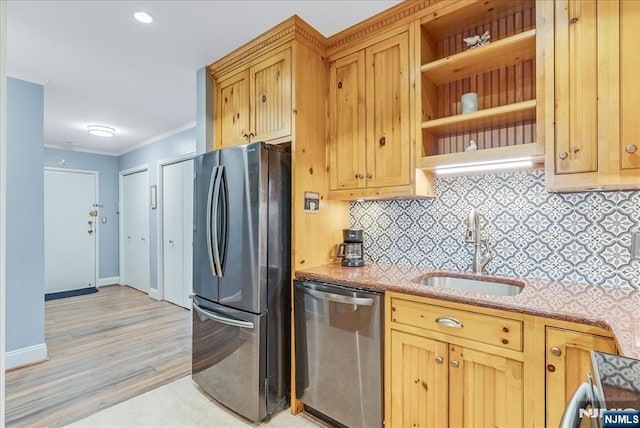 kitchen featuring appliances with stainless steel finishes, a sink, backsplash, ornamental molding, and baseboards