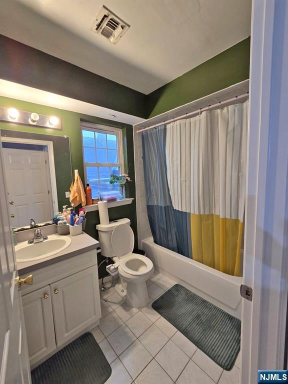 bathroom featuring tile patterned flooring, vanity, toilet, and shower / bath combo with shower curtain