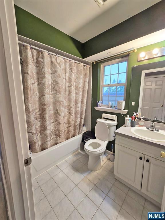 full bathroom featuring tile patterned flooring, toilet, shower / tub combo with curtain, and vanity