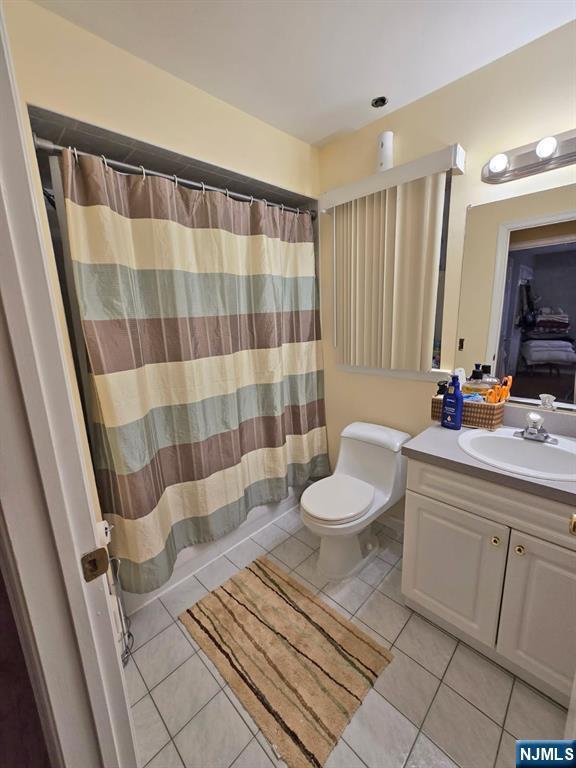 full bath with tile patterned floors, vanity, toilet, and curtained shower