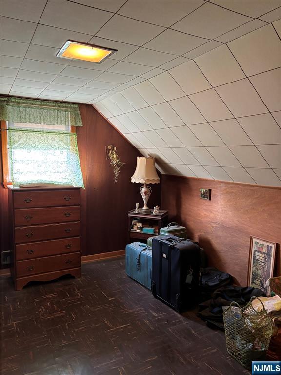 additional living space with vaulted ceiling and wooden walls