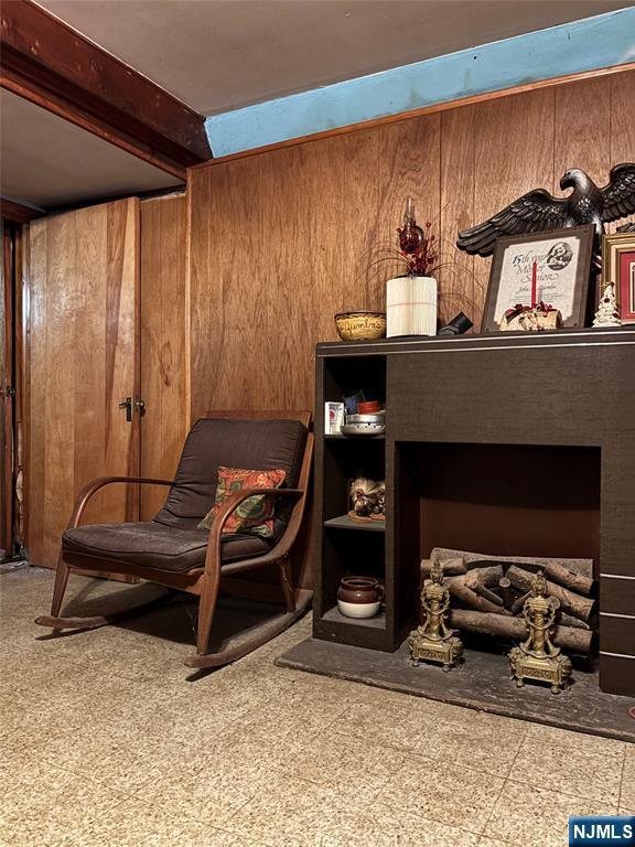 sitting room featuring wood walls, tile patterned floors, and beamed ceiling