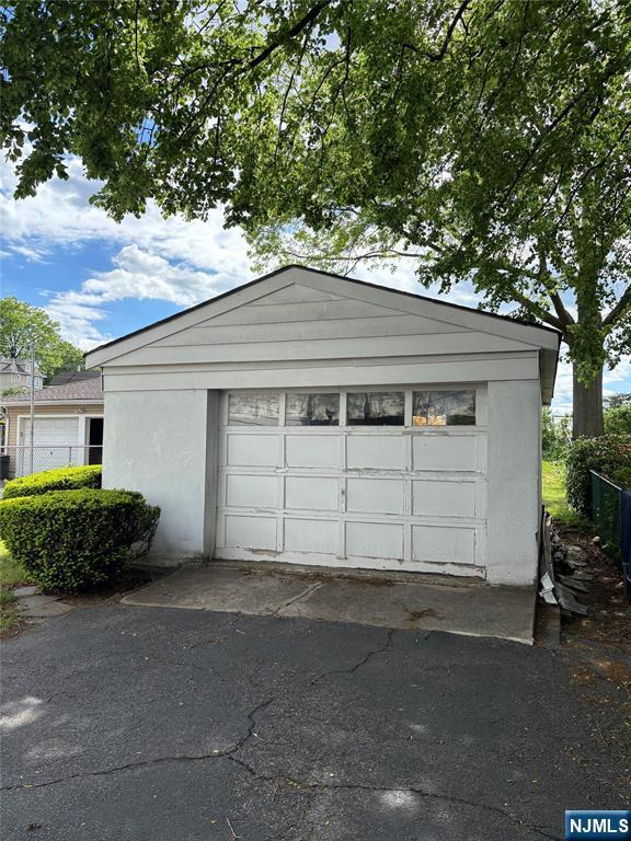 garage featuring fence and asphalt driveway