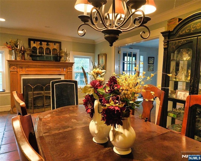 dining space with a chandelier, crown molding, and a fireplace
