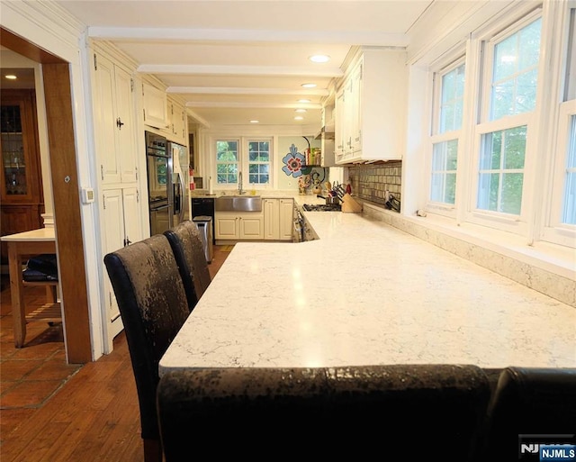 kitchen featuring a sink, a peninsula, plenty of natural light, recessed lighting, and beam ceiling