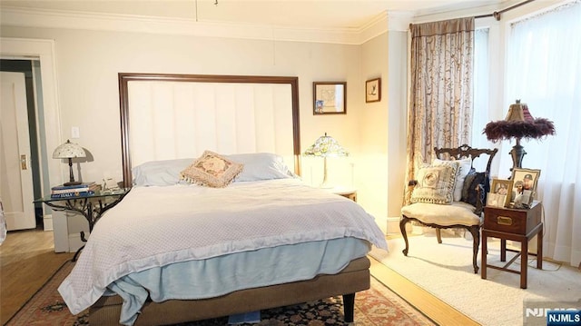 bedroom with crown molding, wood finished floors, and baseboards