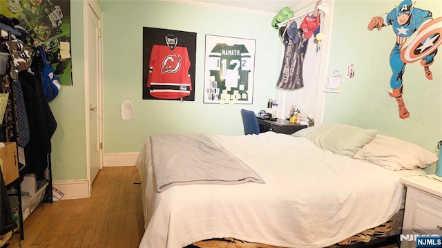 bedroom with wood finished floors, ornamental molding, and baseboards