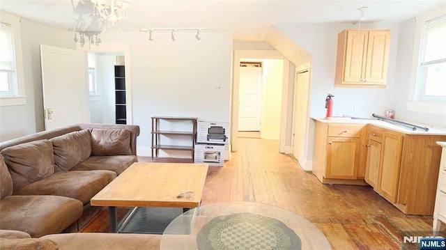 living area with light wood-type flooring, a chandelier, track lighting, and baseboards