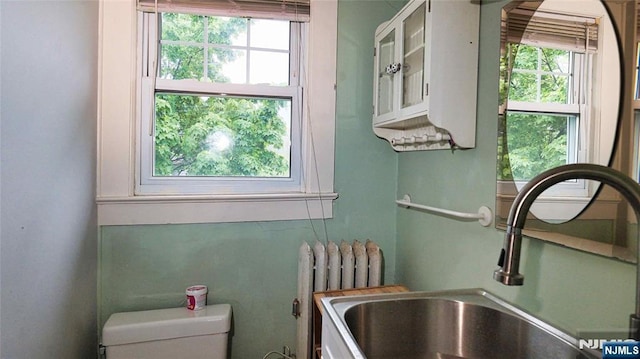 bathroom with radiator, healthy amount of natural light, a sink, and toilet