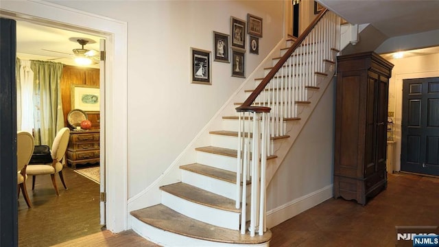 stairs featuring a ceiling fan, wood finished floors, and baseboards