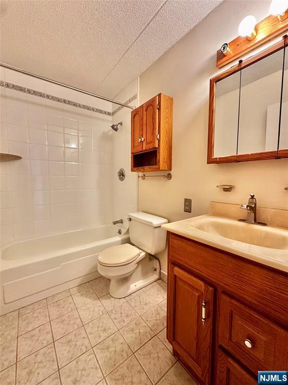 250 Gorge Unit 23A, Cliffside Park, NJ 07010 - bathroom featuring a textured ceiling, toilet, vanity,  shower combination, and tile patterned flooring