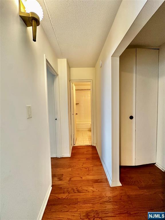 250 Gorge Unit 23A, Cliffside Park, NJ 07010 - hallway with wood finished floors, a textured ceiling, and baseboards