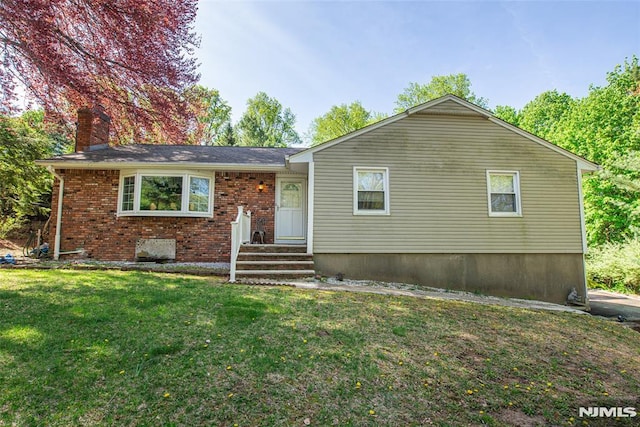 view of front of house featuring a front lawn, brick siding, and a chimney