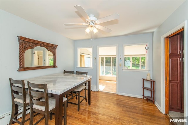 dining room with light wood finished floors, a ceiling fan, baseboards, and a baseboard radiator