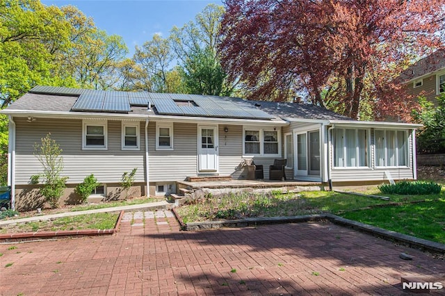 rear view of property featuring solar panels and a sunroom