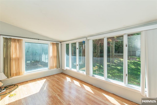 unfurnished sunroom featuring vaulted ceiling and wood finished floors