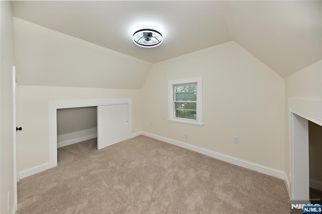 bonus room featuring light colored carpet, lofted ceiling, and baseboards
