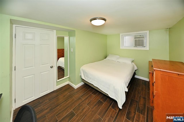 bedroom featuring baseboards, wood finished floors, and a wall mounted air conditioner