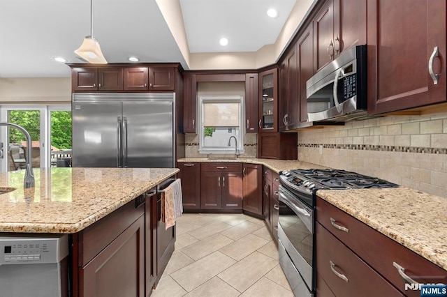kitchen with stainless steel appliances, a sink, light stone counters, decorative backsplash, and recessed lighting