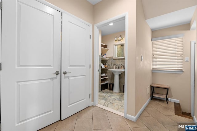 hallway with light tile patterned floors, baseboards, and a sink