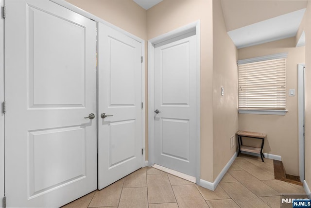 hallway featuring light tile patterned floors and baseboards