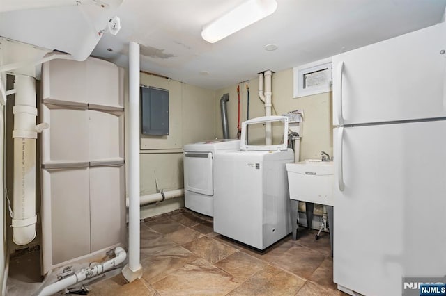 clothes washing area featuring washing machine and clothes dryer, electric panel, and stone finish floors