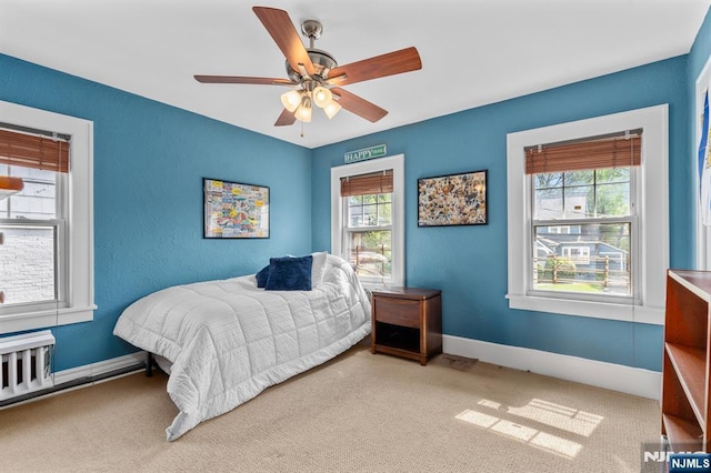 carpeted bedroom featuring baseboards, a ceiling fan, and radiator heating unit