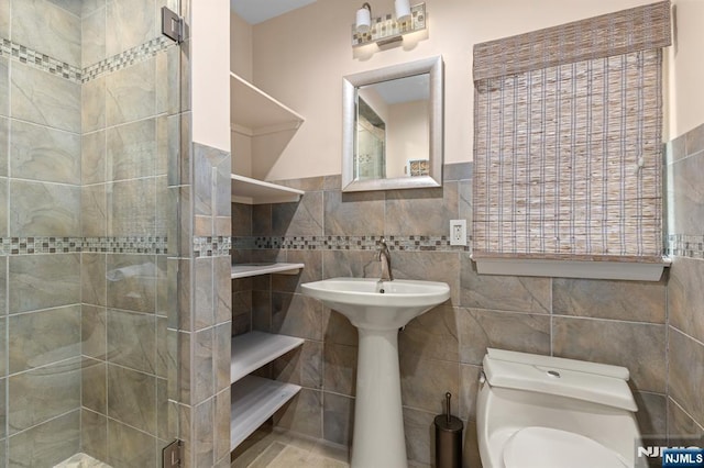 full bathroom with tile walls, a shower stall, toilet, and wainscoting