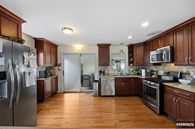 186 10th Ave, Hawthorne, NJ 07506 - kitchen with appliances with stainless steel finishes, a sink, tasteful backsplash, light wood-type flooring, and light stone counters