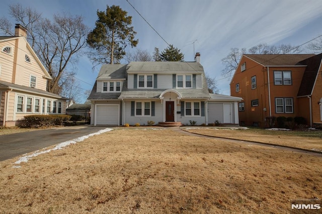 traditional-style house featuring asphalt driveway, a chimney, and a garage