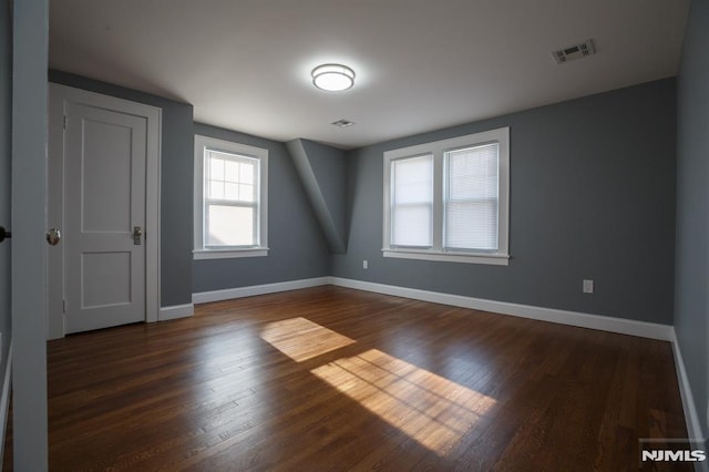 spare room featuring dark wood-style floors and baseboards