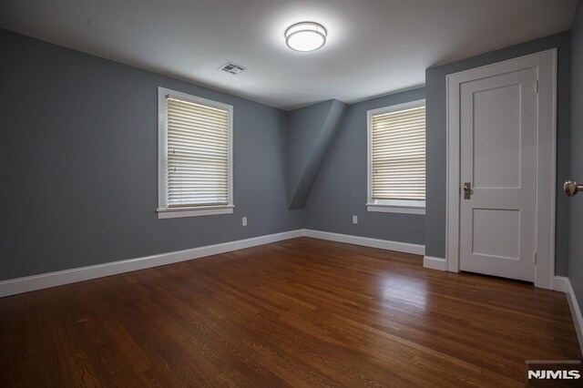 empty room with dark wood finished floors and baseboards
