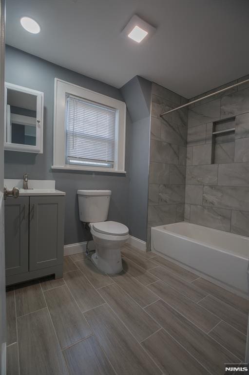 bathroom featuring baseboards, toilet, wood finish floors, vanity, and washtub / shower combination