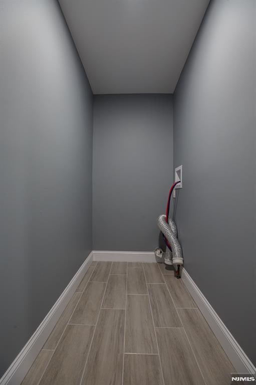 laundry room featuring washer hookup, wood tiled floors, and baseboards