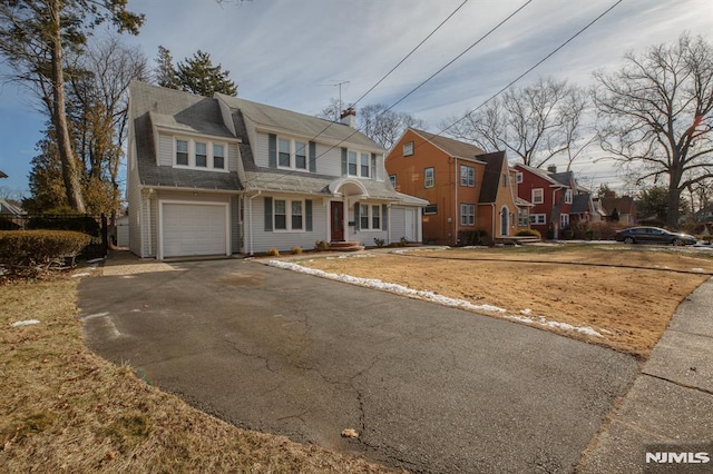 traditional-style home featuring driveway, a residential view, an attached garage, and a shingled roof